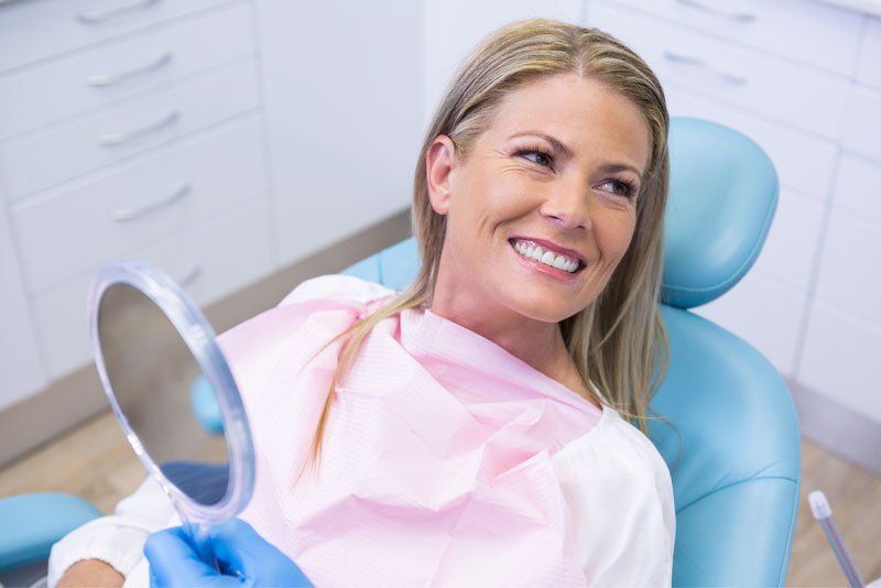 A woman sitting in the dentist chair smiling for the camera.