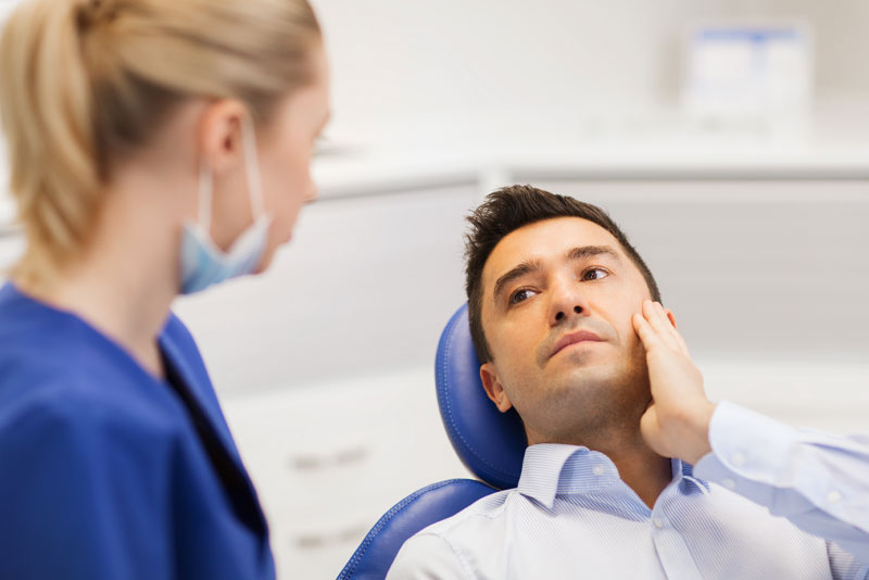 A man sitting in the dentist chair looking at his patient.