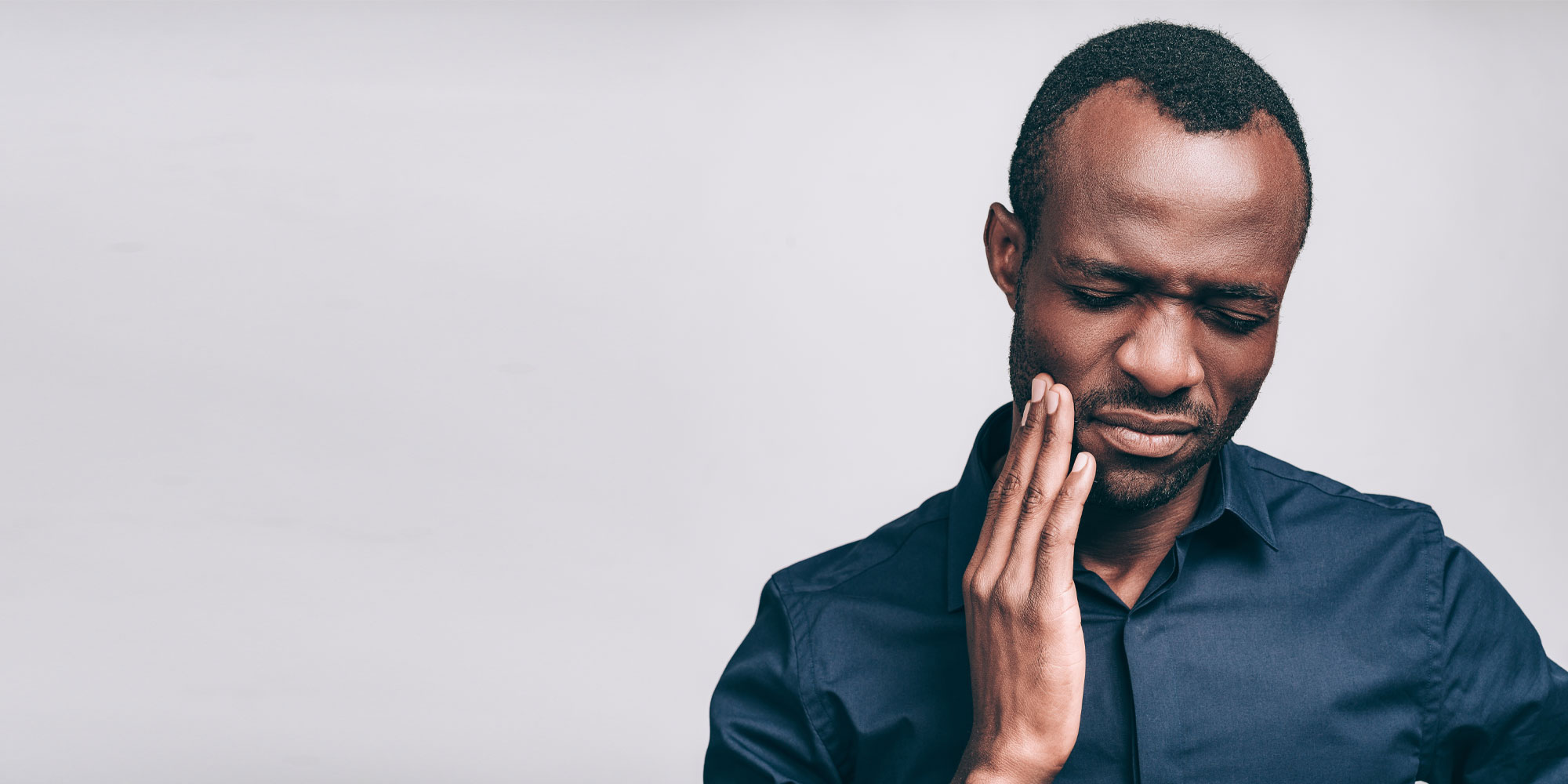 A man with his teeth holding it up to his face.