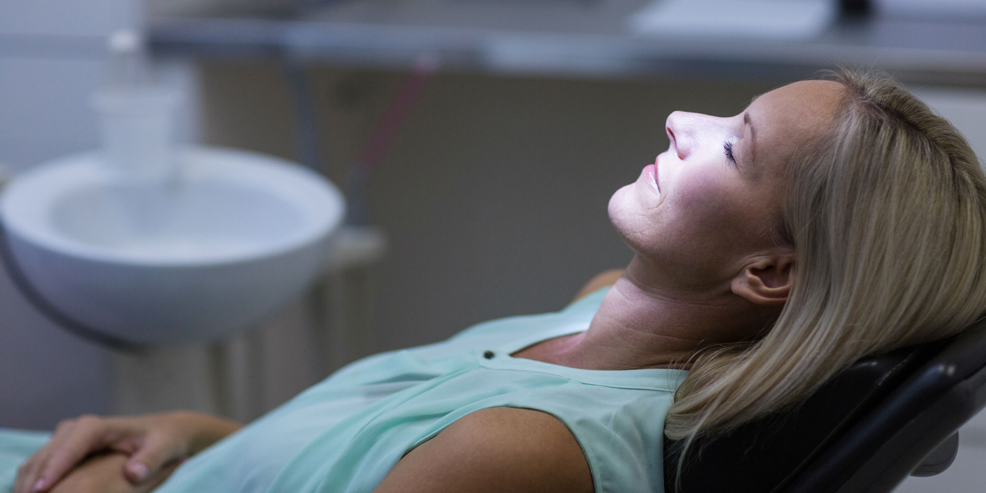 A woman is lying down in the dentist chair.