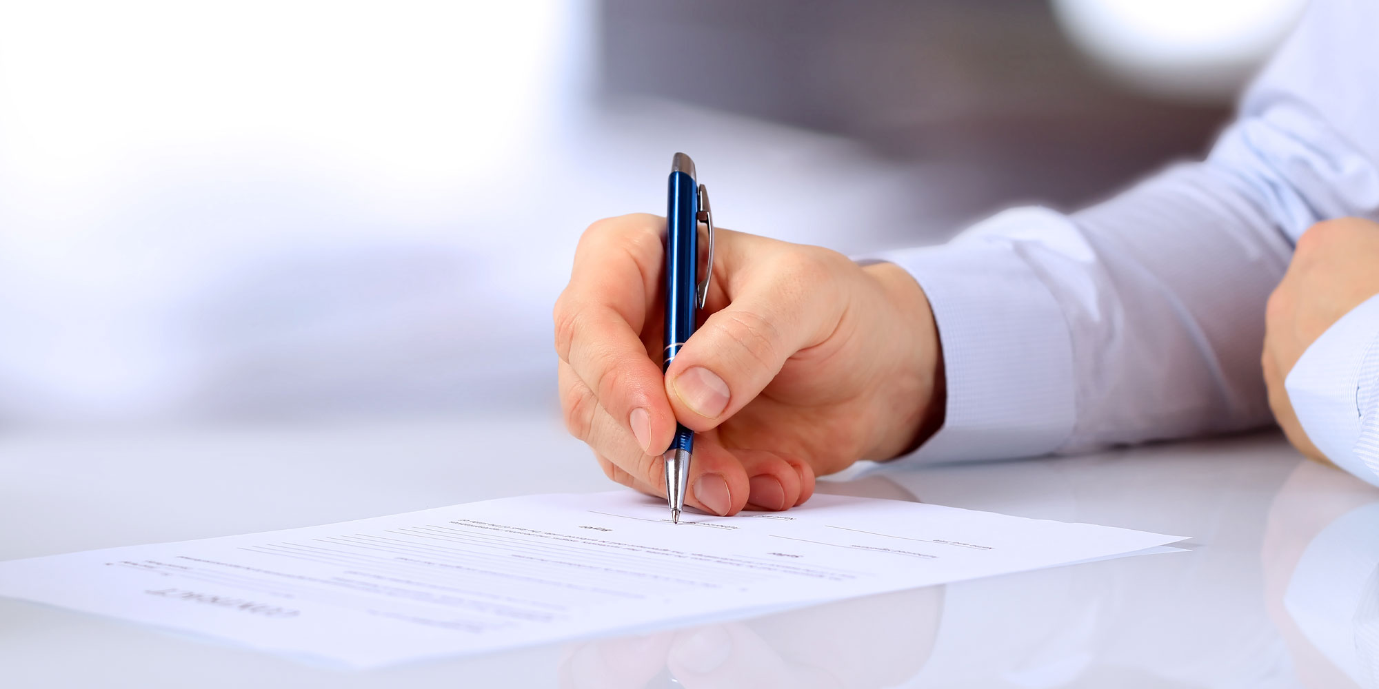 A person writing on paper with a pen.